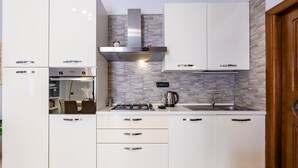 Een moderne keuken met witte kasten, een ingebouwde oven, een gasfornuis en een roestvrijstalen afzuigkap.