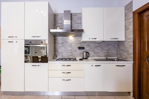 Eine moderne Küche mit weißen Schränken, einem eingebauten Backofen, einem Gasherd und einer Edelstahl-Dunstabzugshaube.