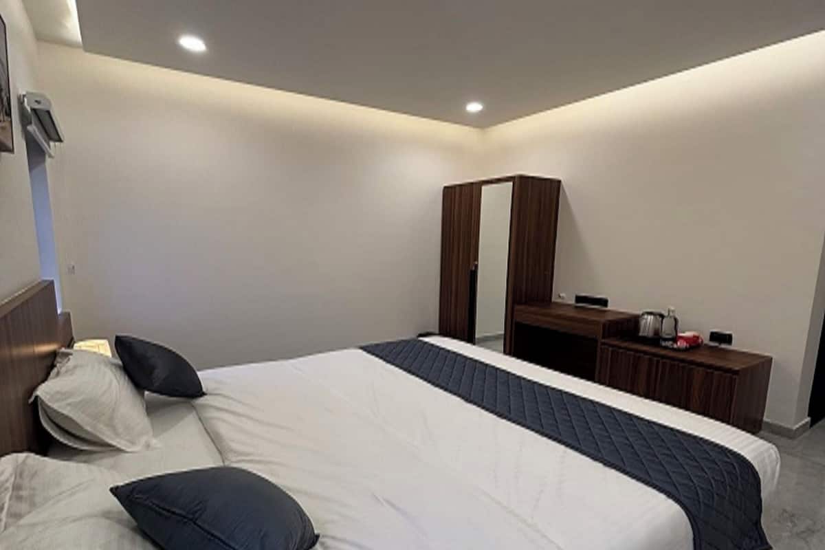 A modern bedroom with a large bed, a wardrobe, and a mirror.