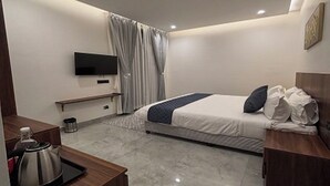 A modern hotel room with a bed, a TV, a desk with a kettle, and a shower area. - Fairy heights  (Kodaikanal)