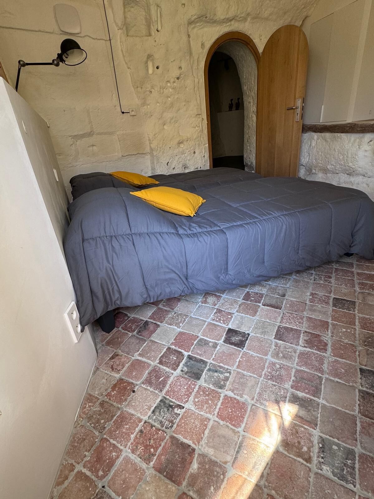 Une chambre à coucher avec un lit, une porte en bois et un sol carrelé.