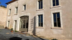 A two-story building with a beige facade, multiple windows, and a central entrance with a glass door. - Family suite in troglodyte house with access to indoor swimming pool (La Roche-Clermault)