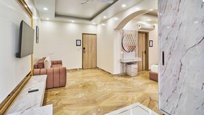 A spacious room with a marble floor, a ceiling fan, a television, and a seating area with a cushioned sofa.