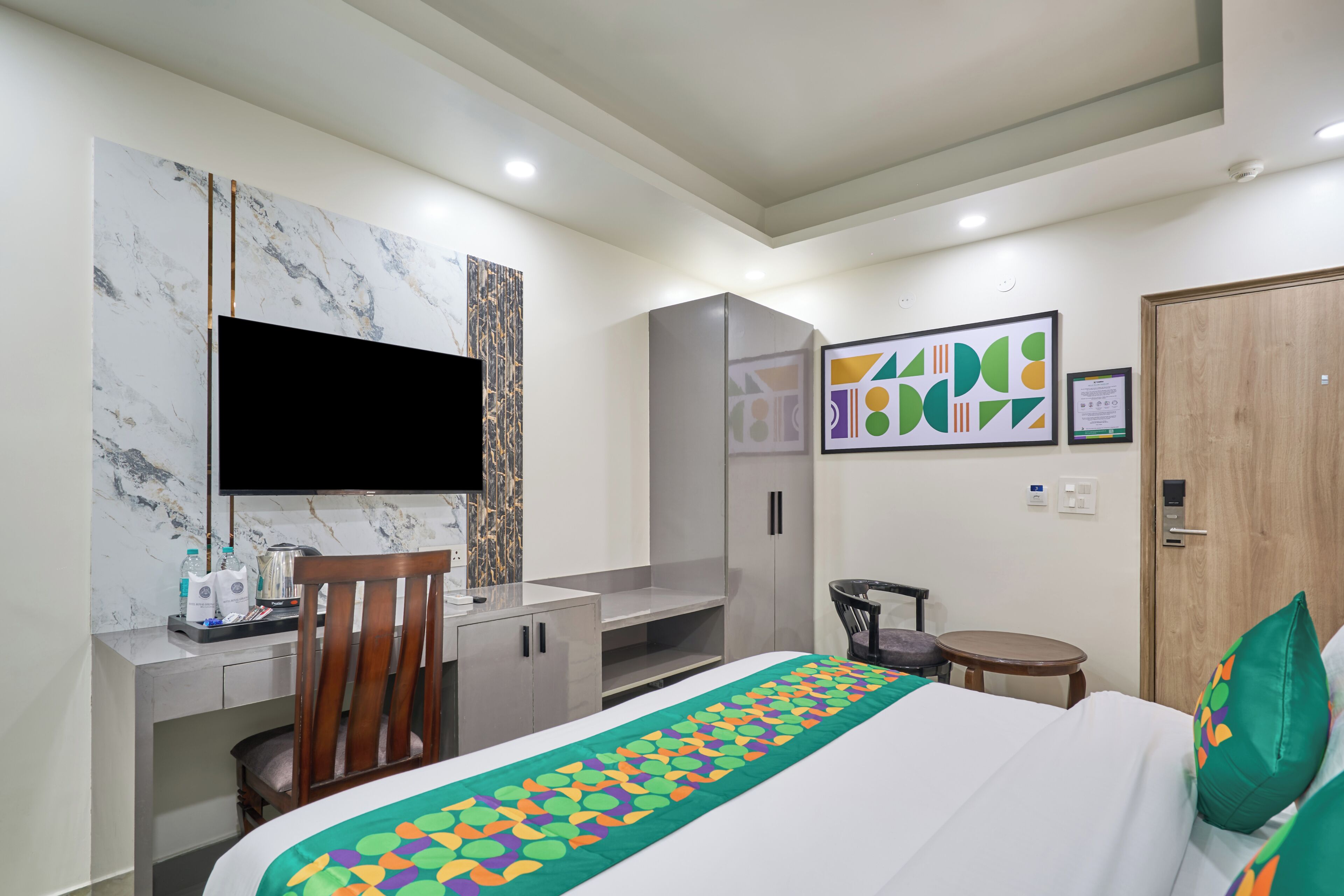 Ein Hotelzimmer mit Bett, Schreibtisch, Stuhl, Fernseher und Kleiderschrank.