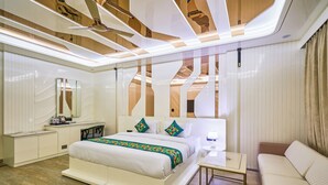 A modern hotel room with a large bed, bedside tables, a sofa, and a ceiling with wooden beams.