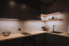 A modern kitchen with a wooden countertop, a black sink, and built-in cabinets.