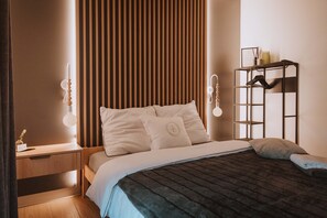 Une chambre bien rangée, avec un lit, une table de chevet et une étagÚre fixée au mur.