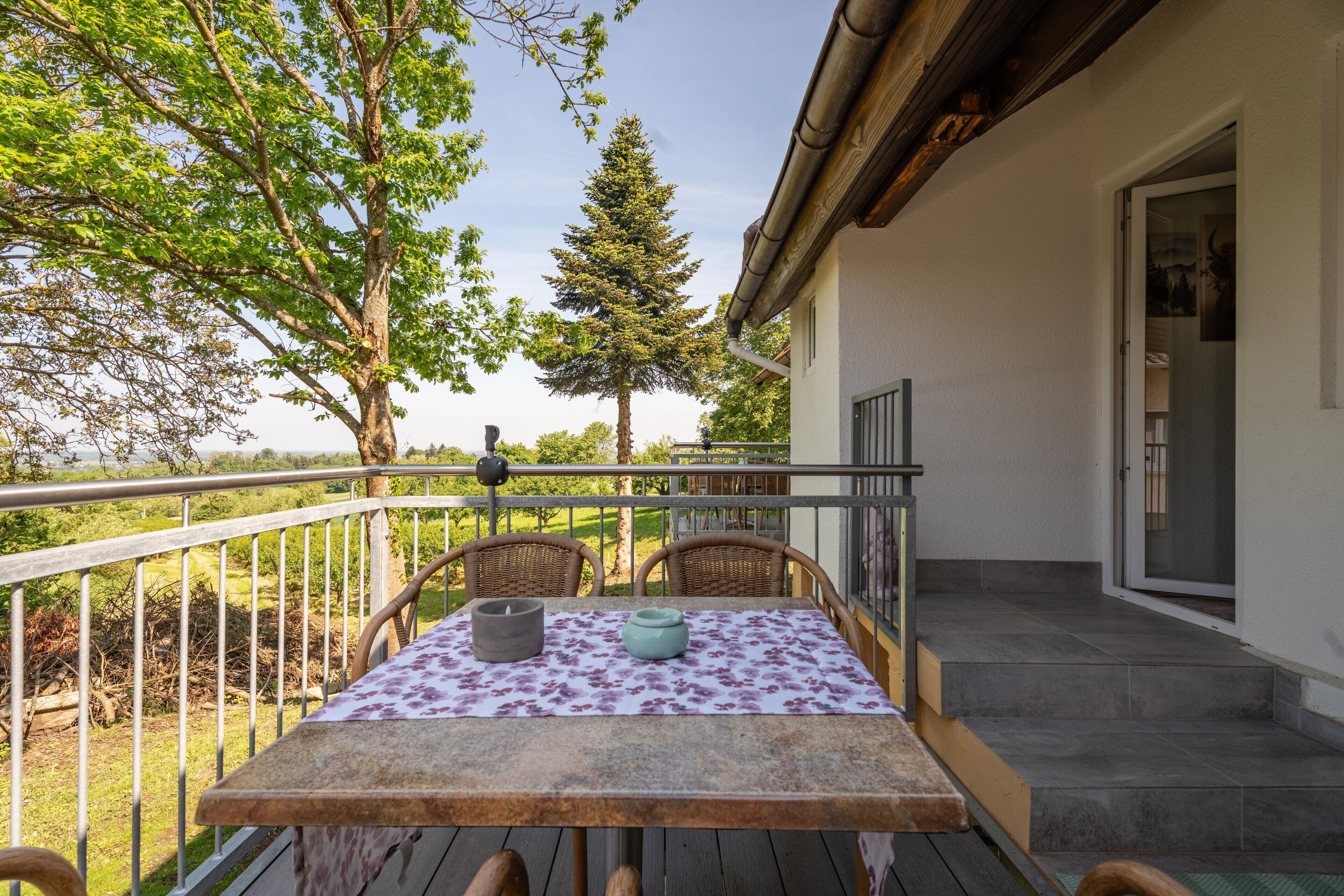 A balcony with a table, chairs, and a view of the landscape.