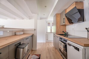 Une cuisine moderne avec des plans de travail en bois, un four encastré et un lave-vaisselle.
