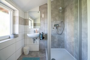 Une salle de bain moderne avec une douche à parois de verre, un lavabo et un miroir.