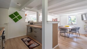 Une cuisine moderne avec un plan de travail en bois, un coin repas avec une table et des chaises, et une grande fenêtre.