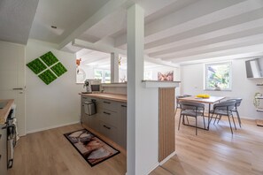 Eine moderne Küche mit Holzarbeitsplatte, einem Essbereich mit Tisch und Stühlen sowie einem großen Fenster.
