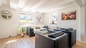 Un salon moderne avec un canapé, une table basse en verre et un tableau représentant un taureau.