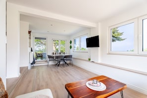 Un interno moderno con un'area pranzo, una TV a parete e ampie finestre.