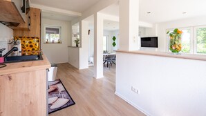 Eine moderne Küche mit Holzausstattung, einem eingebauten Ofen und einem Essbereich mit Tisch und Stühlen.