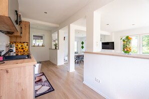 A modern kitchen with wooden cabinets, a built-in oven, and a dining area with a table and chairs.