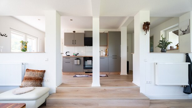Una sala de estar moderna con un sofá, una mesa de madera y vistas a la cocina.