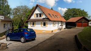 Ein zweistöckiges Haus mit rotem Ziegeldach, einer Auffahrt und einem geparkten blauen Auto.