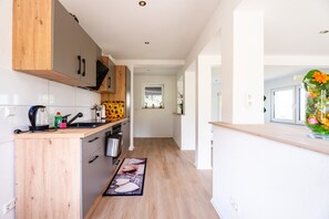 A modern kitchen with wooden cabinets, a built-in oven, and a window.
