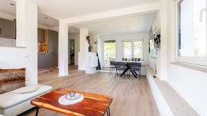 Ein modernes Wohnzimmer mit Holztisch, einer Couch und einem Essbereich mit Stühlen.