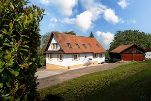 Una casa a due piani con tetto inclinato, un portico e un garage.