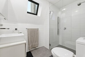 Ein modernes Badezimmer mit Toilette, Waschbecken und Duschkabine aus Glas.