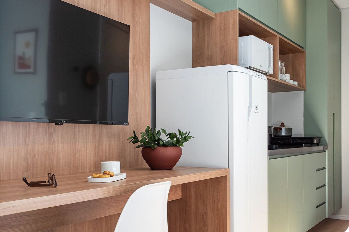 Una cocina compacta con refrigerador empotrado, televisor de pantalla plana y encimera de madera.