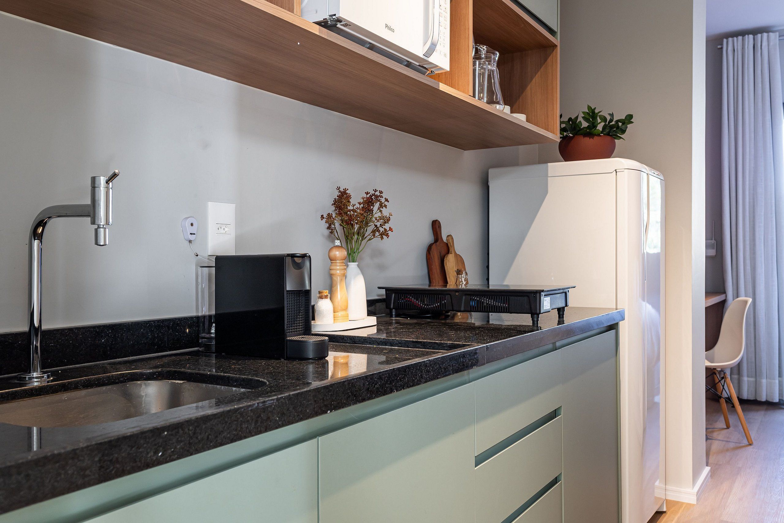 A modern kitchen with a granite countertop, a built-in dishwasher, and a white refrigerator.