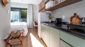 A modern kitchen with a refrigerator, microwave, and wooden shelves. - Casa Omaguás by Viva | Apartamentos modernos no coração de Pinheiros (São Paulo)