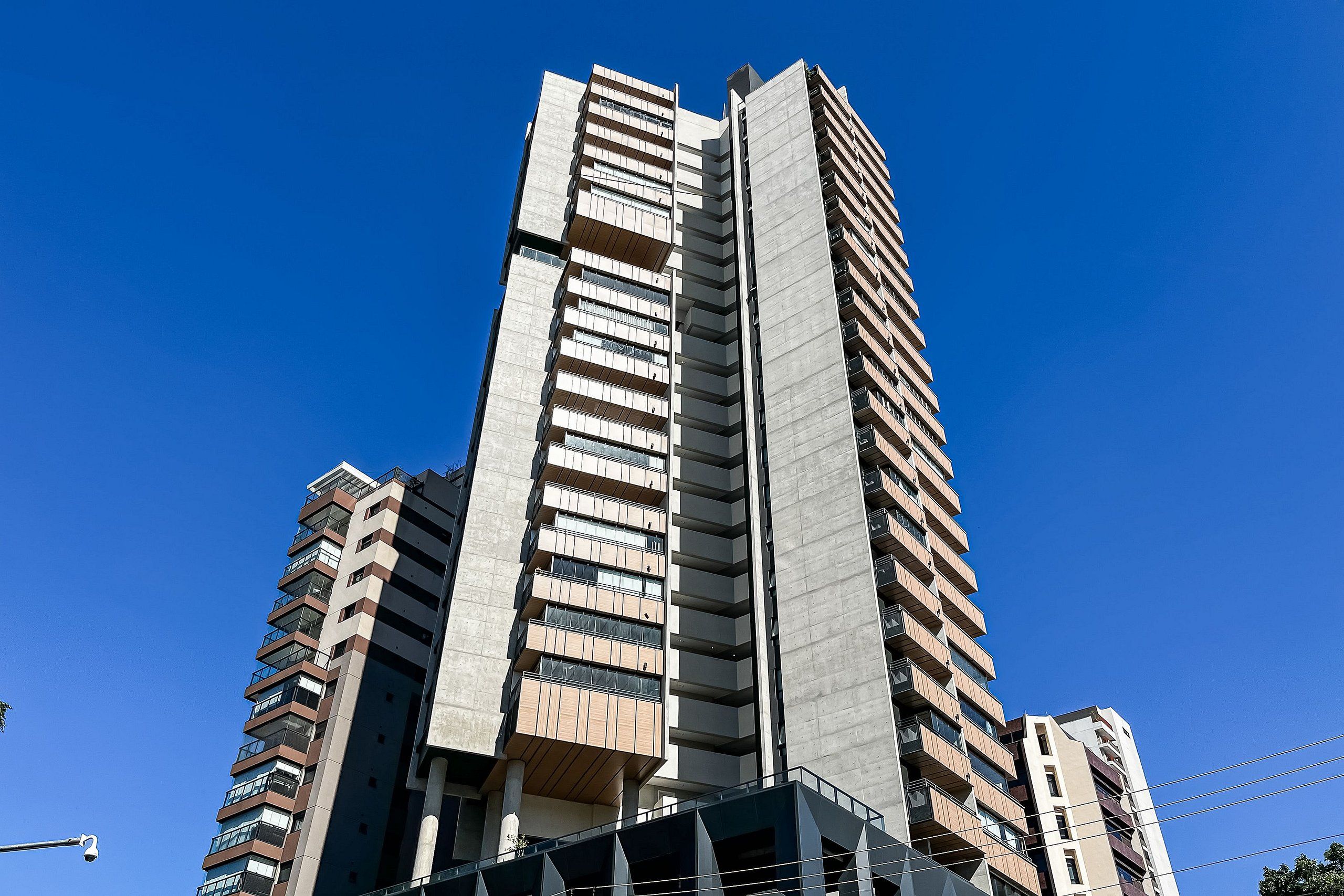 A high-rise building with multiple balconies and a clear blue sky.