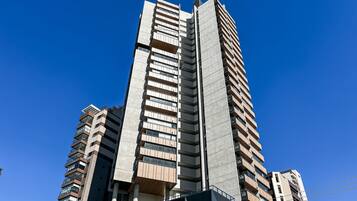 A high-rise building with multiple balconies and a clear blue sky.