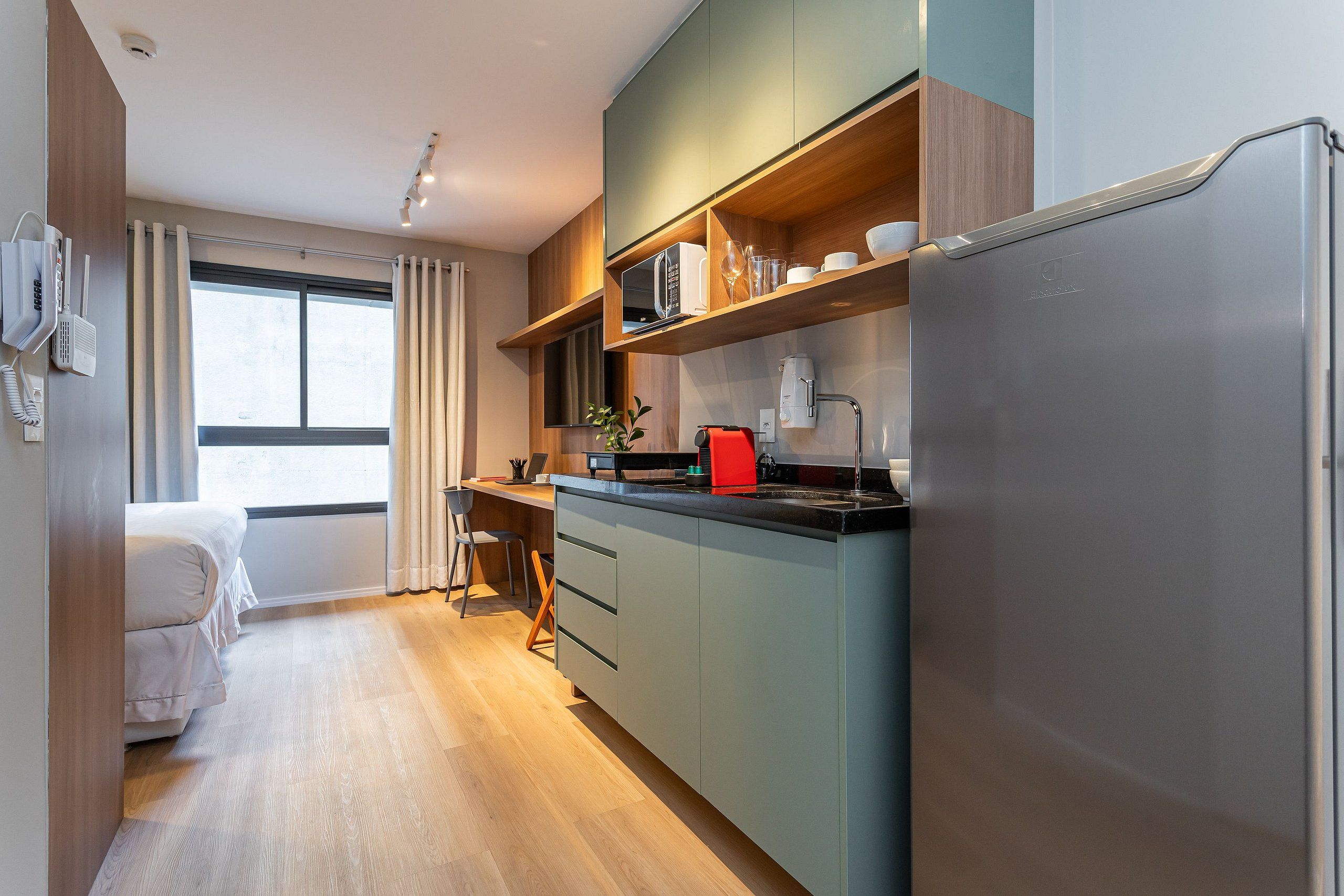 A compact kitchen with a built-in microwave, a coffee machine, and a refrigerator.