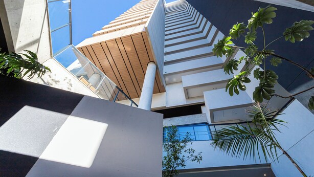 A modern building with a unique architectural design, featuring a combination of glass and wooden elements, and a view of the sky through the structure. - Casa Omaguás by Viva | Apartamentos modernos no coração de Pinheiros (São Paulo)