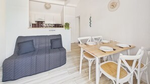 Un soggiorno moderno con divano, tavolo da pranzo, sedie e cucina sullo sfondo.