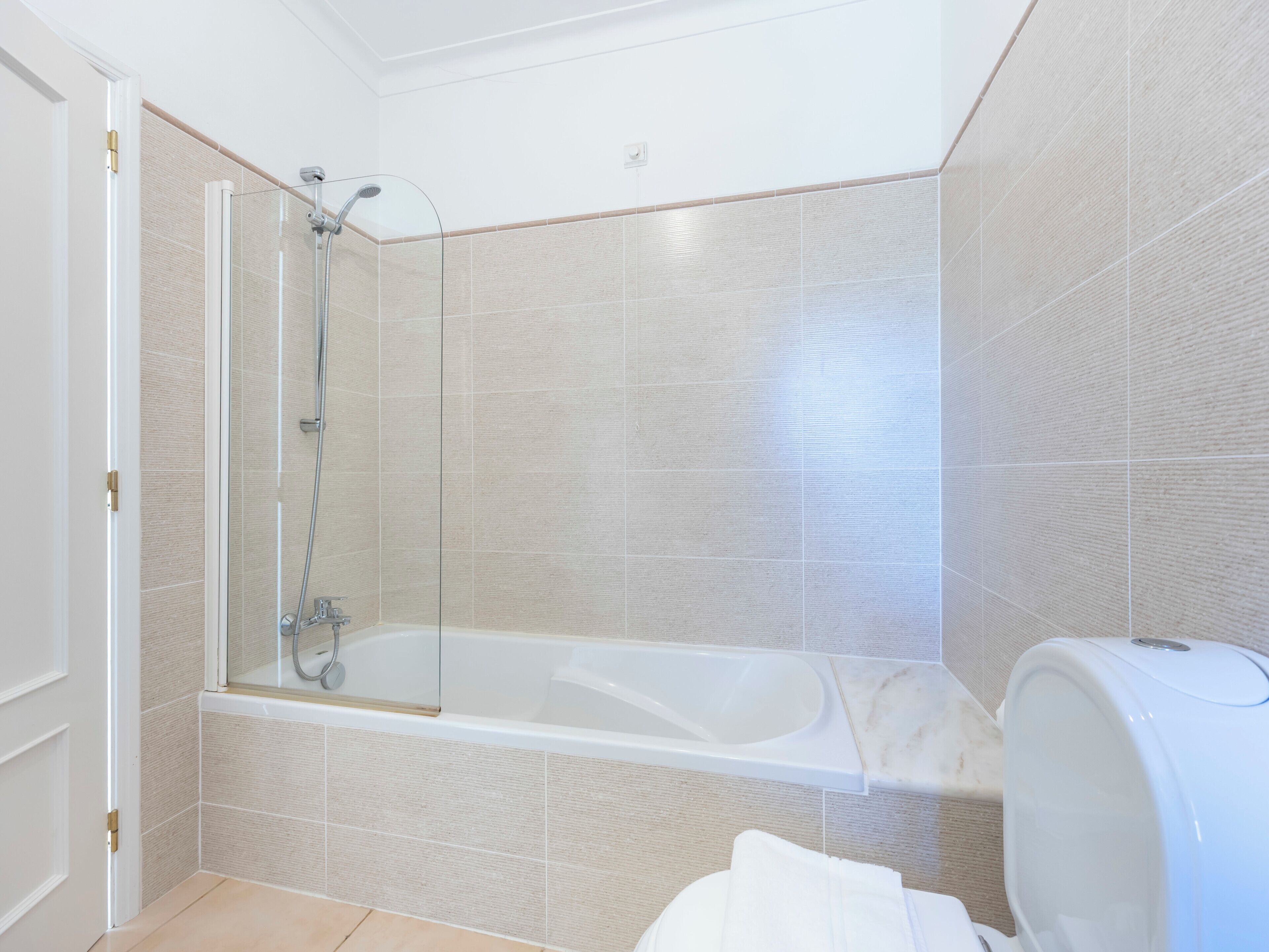 A bathroom with a glass-enclosed shower, a bathtub, and a toilet.