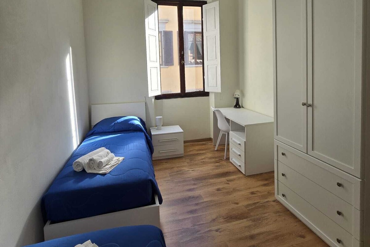 Une petite chambre individuelle comprenant un lit, un bureau, une armoire et une fenêtre.