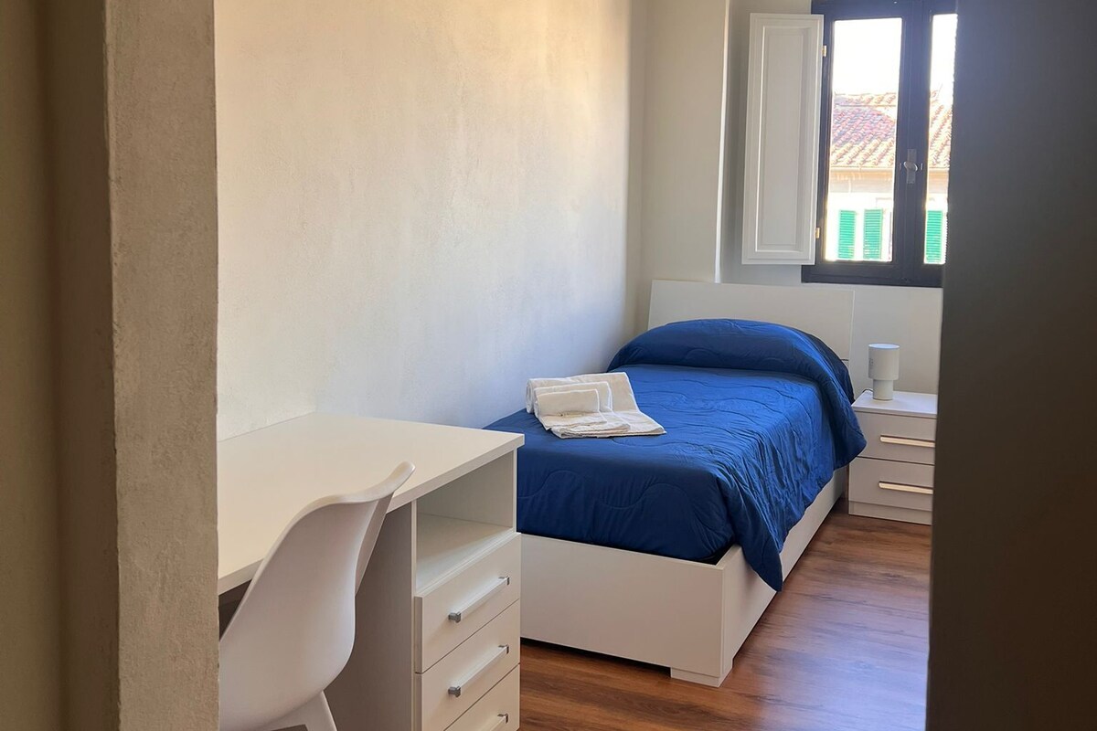 Une chambre à coucher avec un lit, un bureau et une fenêtre.