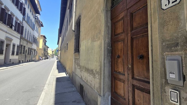 A street view with a building featuring a large wooden door and a number '52' sign. - Casa per Ferie degli Angiolini (Florence)
