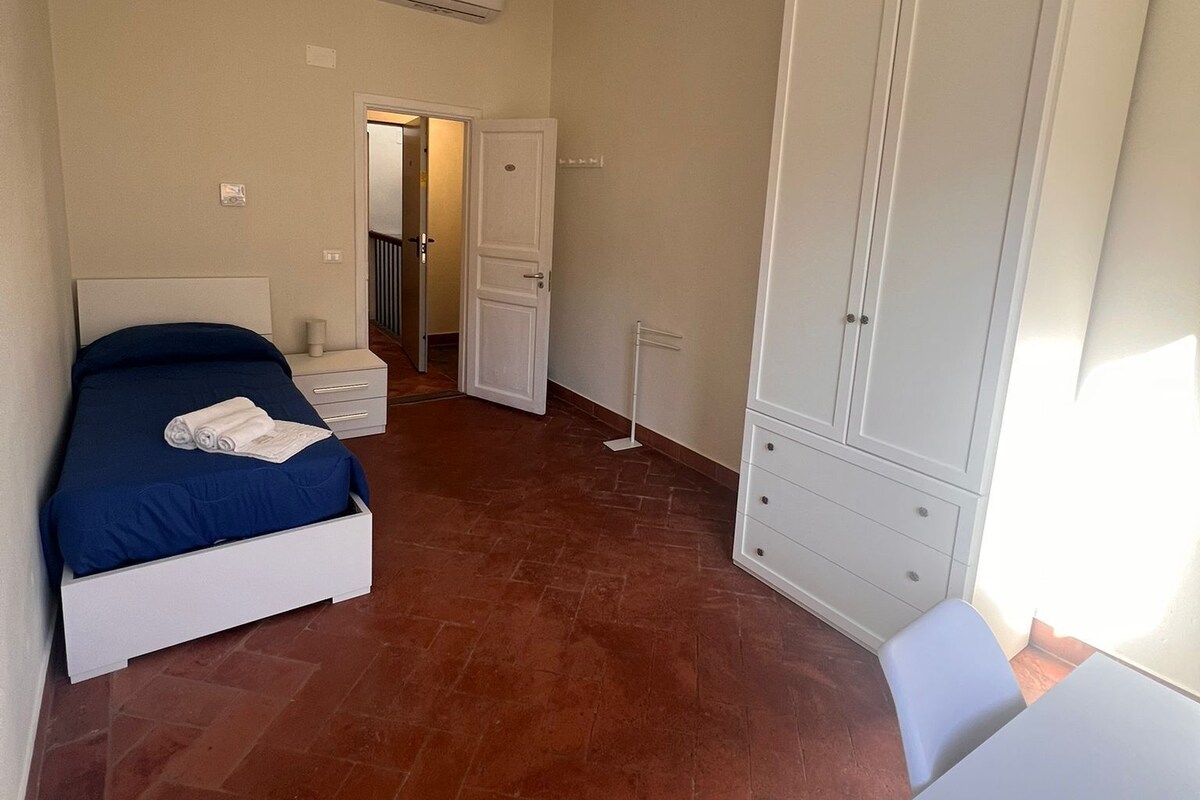 Une chambre à coucher avec un lit, une armoire, une porte et un sol carrelé.