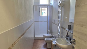 A narrow bathroom with a shower, toilet, bidet, and sink. - Casa per Ferie degli Angiolini (Florence)