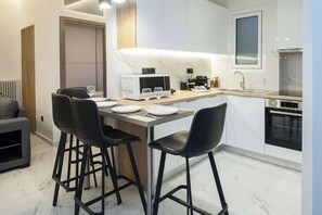 A modern kitchen with a dining area, including a microwave, coffee maker, and a sink. - Modern Designer 1 Bd Apt in Central Athens (Athina)