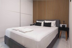 A modern hotel room with a large bed, a wooden panel wall, and a black nightstand with a lamp. - Modern Designer 1 Bd Apt in Central Athens (Athina)