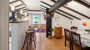 Een kamer met een houten plafond, een eettafel met stoelen, een bar met krukken en uitzicht op het omliggende landschap.