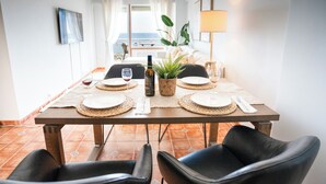 Ein Essbereich mit einem Tisch für vier Personen, einer Weinflasche und einem Blumentopf.