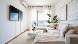 Un salon moderne avec un canapé, une table basse et un téléviseur fixé au mur.