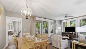 Un salón espacioso con una mesa de comedor, sillas, sofá, televisor y ventilador de techo.