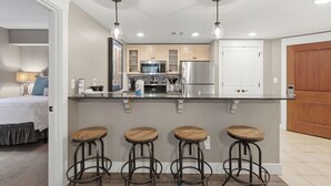 Una cocina moderna con una isla central, taburetes de bar y electrodomésticos de acero inoxidable.