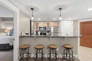 A modern kitchen with a central island, bar stools, and stainless steel appliances. - RARE! Corner Unit Connected to Baytowne Wharf! Trop Pool, Hot Tub, Beach Tram (Miramar Beach)