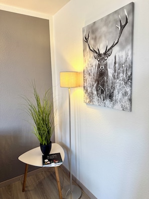 Ein Zimmer mit Stehlampe, Topfpflanze und einem gerahmten Wildtierfoto an der Wand.