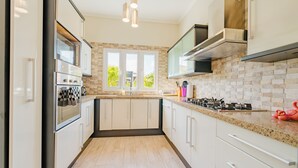 A modern kitchen with built-in appliances, a large window, and a view of greenery outside. - Palm Beach Retreat 2 bed - 2 Bath Private (Noord)